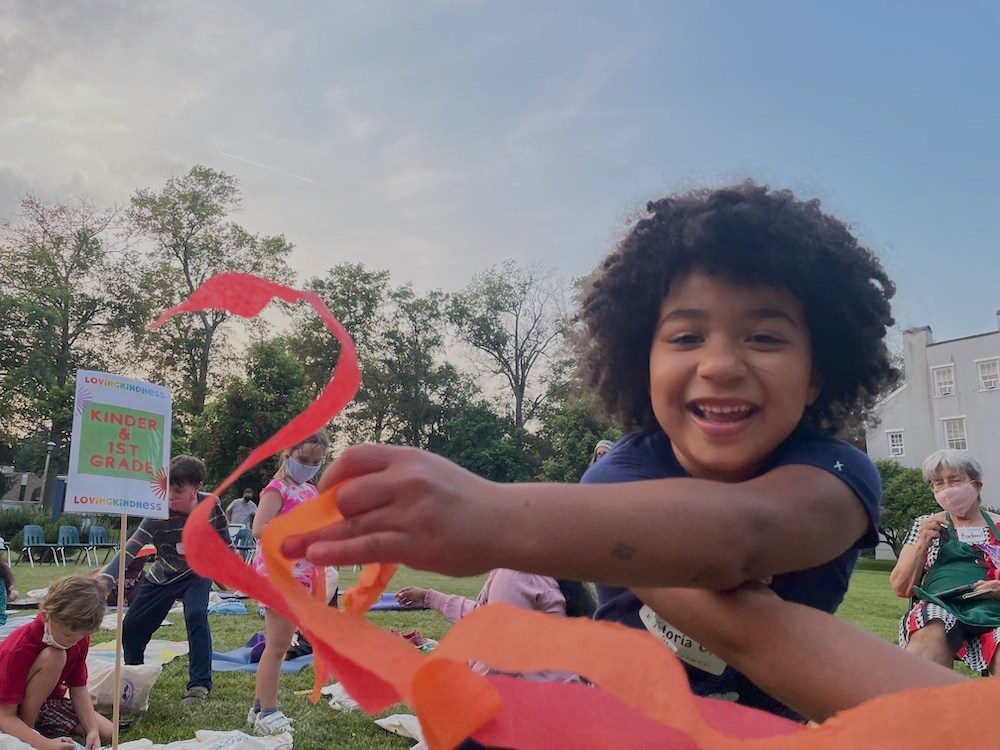 smiling child waves streamers at outdoor VBS